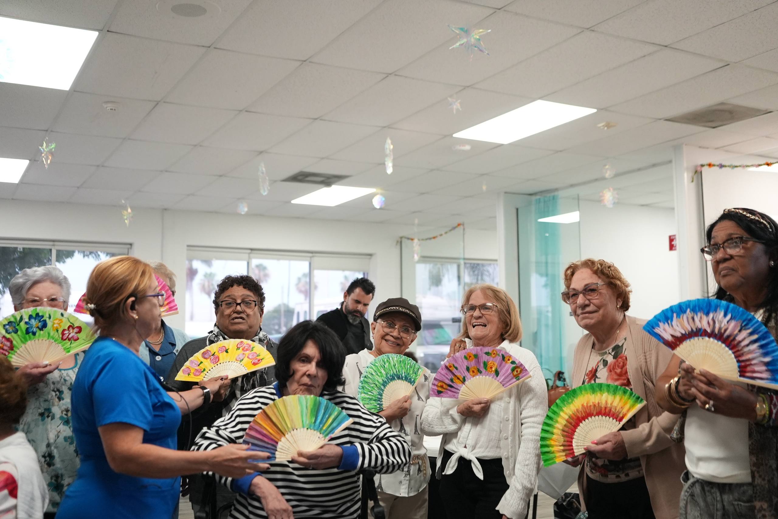 Grupo de miembros de Xclusive Senior Care mostrando abanicos pintados